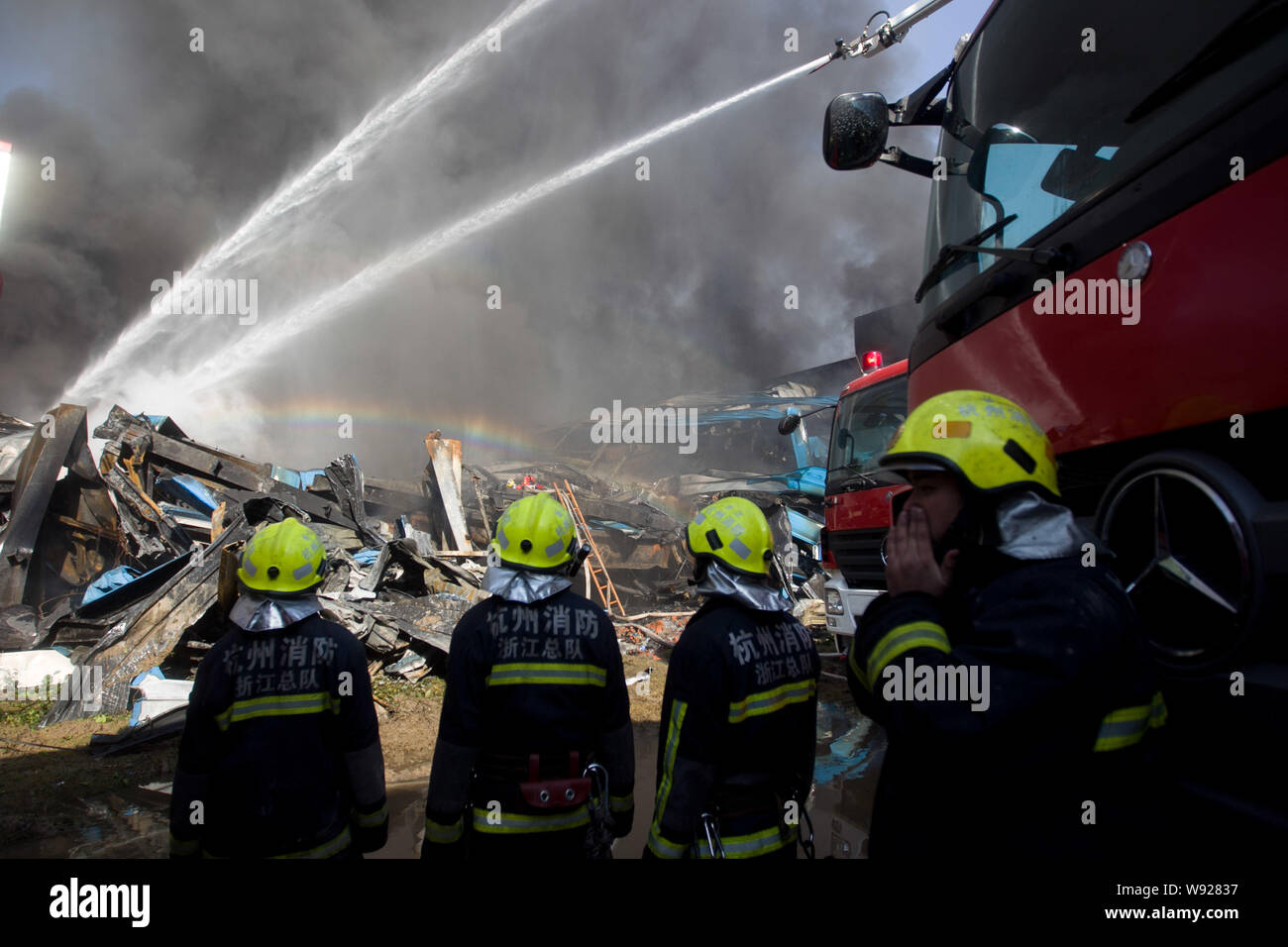 Chinese firefighters watch water being hosed to extinguish the fire at ...