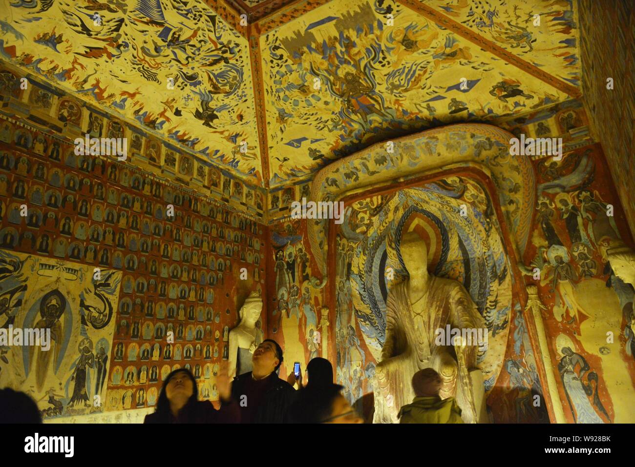 Visitors view replicas in a replicated chamber of the Mogao Grottoes ...