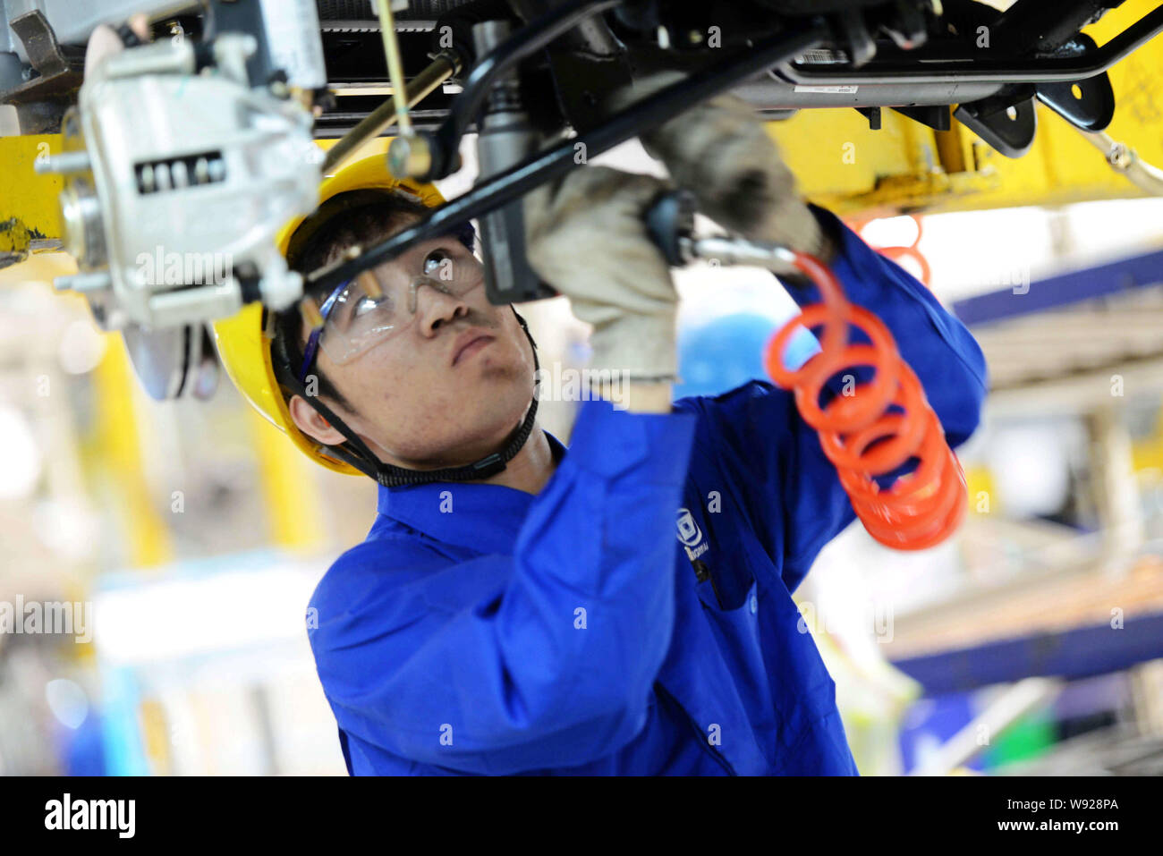 A Chinese worker assembles a car on an assembly line at a plant of SAIC ...