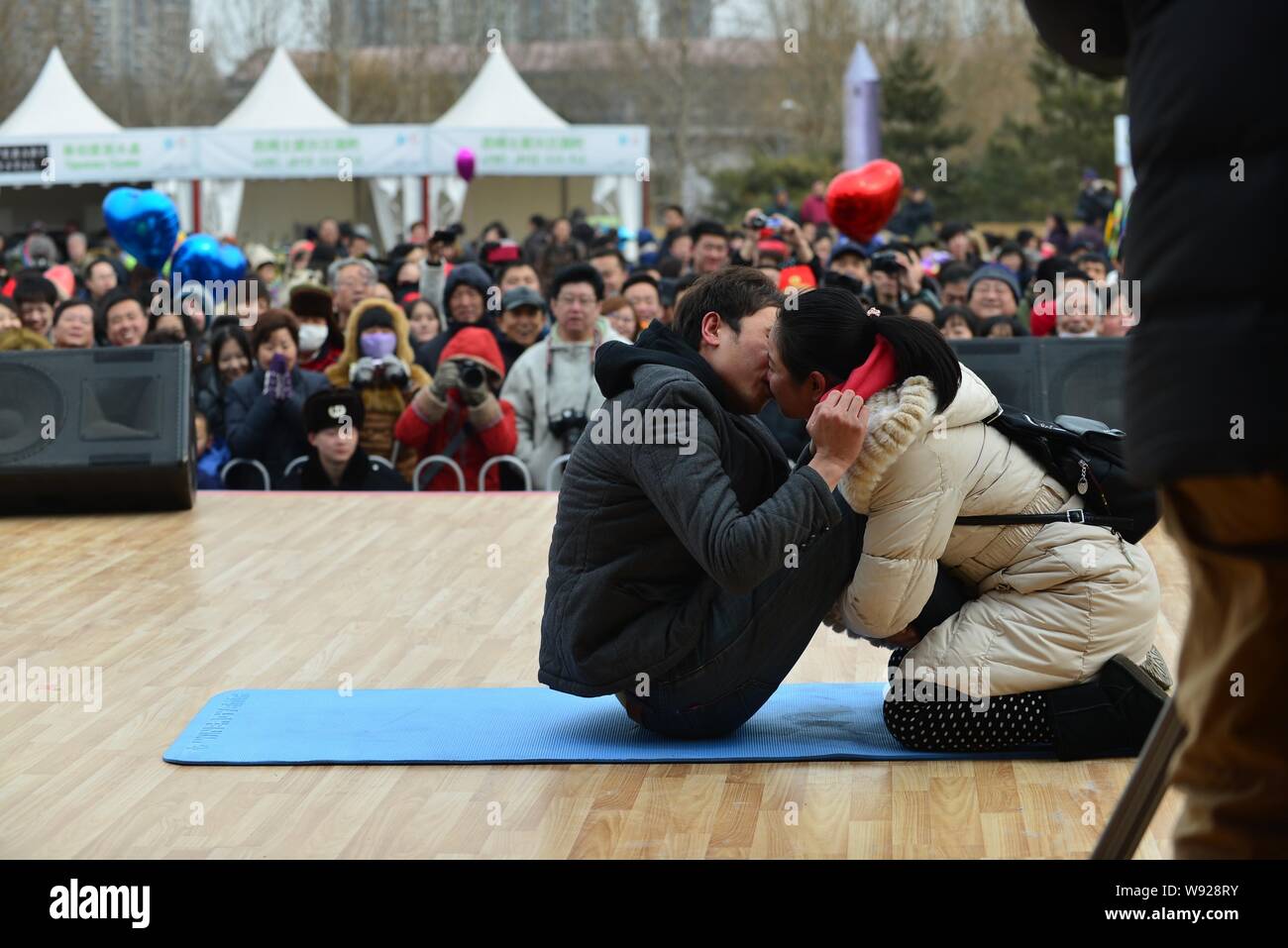 A couple of Chinese lovers kiss in the position of bent-knee sit-up during a kissing competition on the Valentines Day in the Happy Valley in Beijing, Stock Photo
