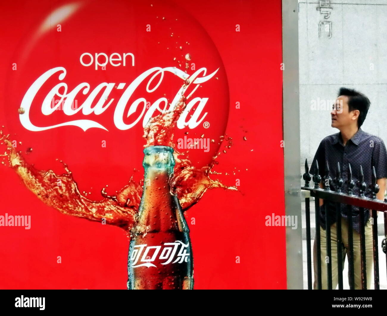 FILE--A pedestrian walks past an advertisement of Coca-Cola in Shanghai,  China, 9 September 2011. The Coca-Cola Company announced that it will con  Stock Photo - Alamy