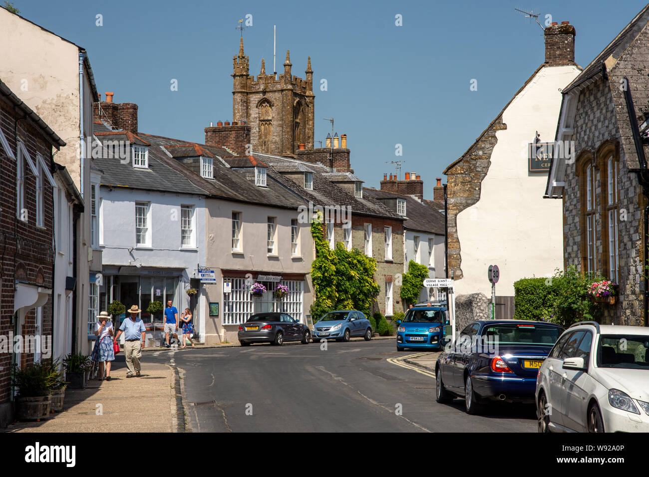 Cerne Abbas, England, UK - June 29, 2019: Pedestrians walk past traditional cottages on Long Street in the picturesque village of Cerne Abbas in Dorse Stock Photo