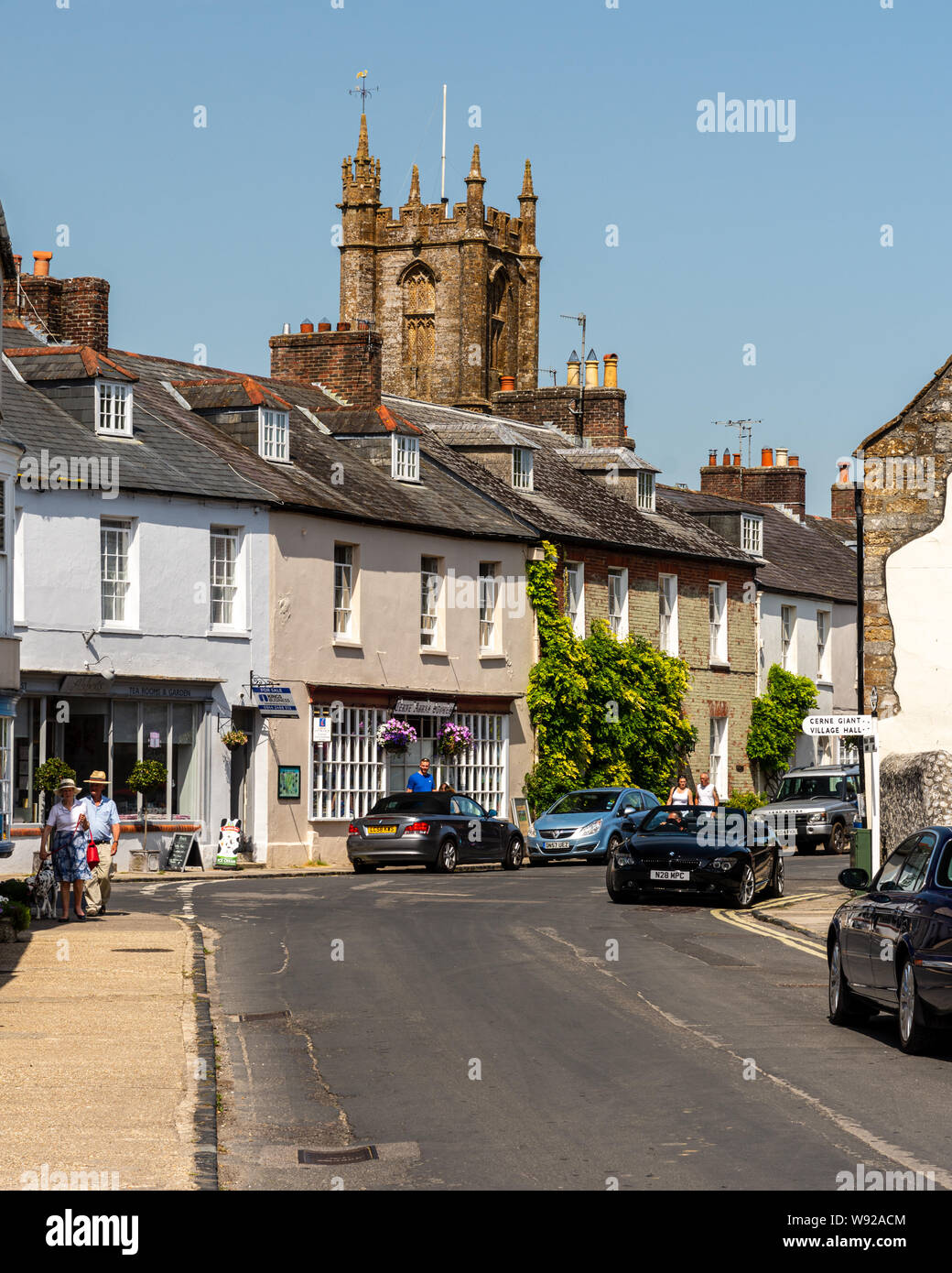 Cerne Abbas, England, UK - June 29, 2019: Pedestrians walk past traditional cottages on Long Street in the picturesque village of Cerne Abbas in Dorse Stock Photo