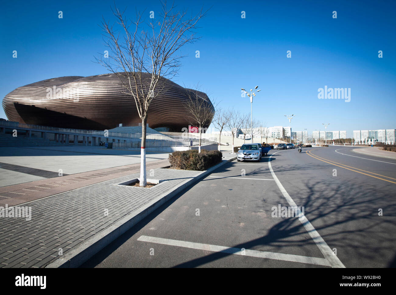 Cars are parked on a nearly empty road in front of the Ordos Musuem in ...