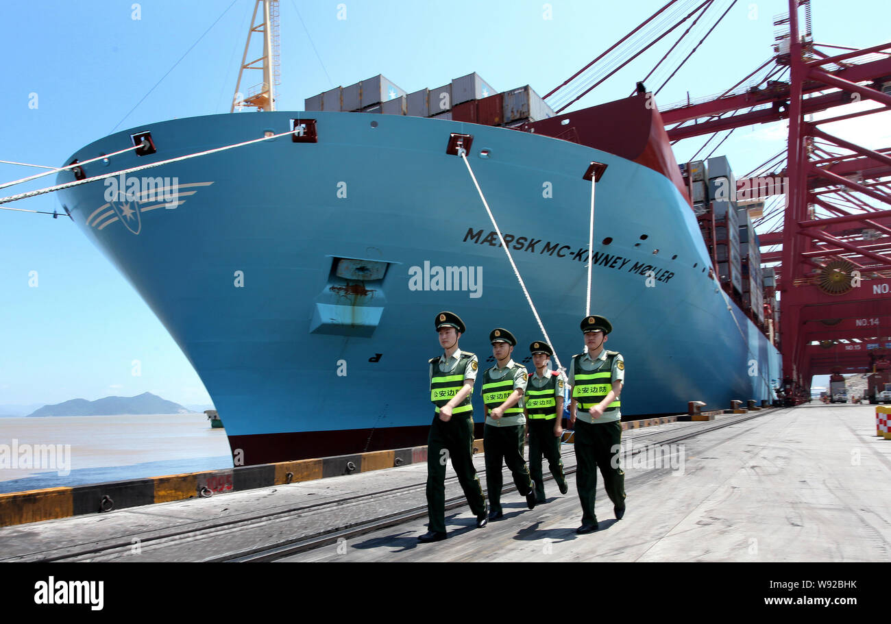 Chinese public securities walk past the Maersk Mc-Kinney Moeller Triple-E class container vessel, the worlds largest ship as it arrives at the Ningbo Stock Photo