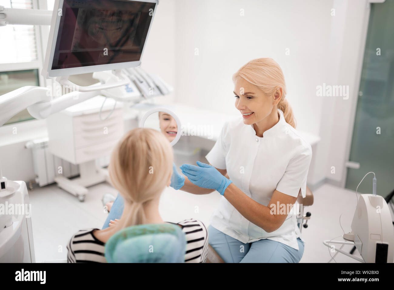 Dentist showing the patient her teeth in the mirror Stock Photo - Alamy