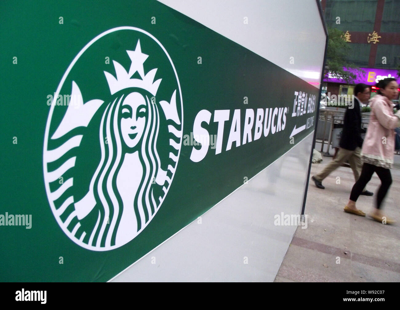 File Pedestrians Walk Past An Advertisement For Starbucks Coffee In Nanjing East Chinas Jiangsu Province 18 April 13 The High Prices For Sta Stock Photo Alamy