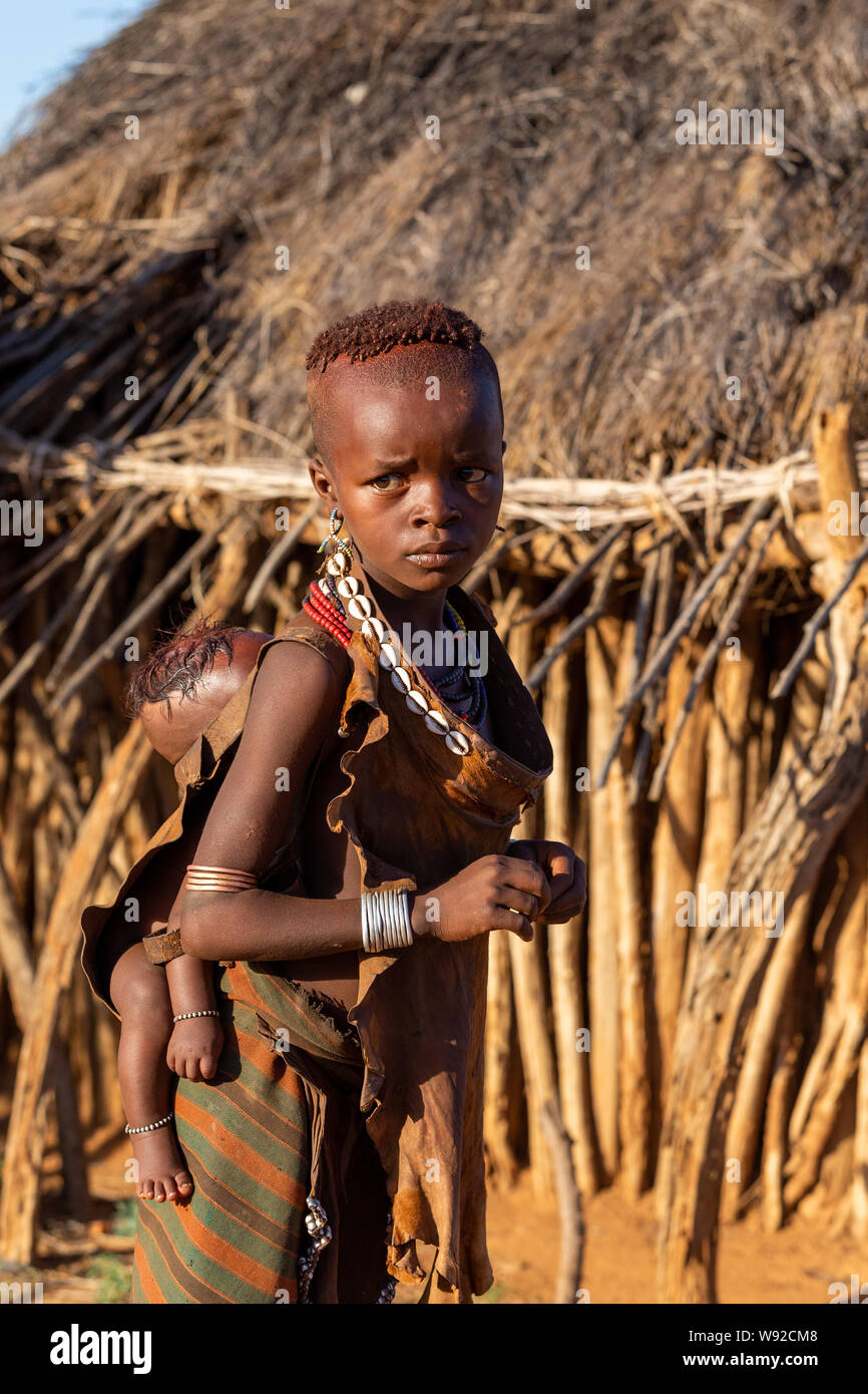 Turmi, Omo River Valley, Ethiopia - May 10, 2019: Portrait of a Hamar children with with baby on back in village. The Hamer are a primitive tribe and Stock Photo