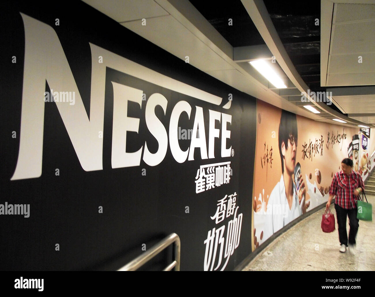 --FILE--A pedestrian walks past an advertisement for Nescafe of Nestle in Nanjing, east Chinas Jiangsu province, 2 June 2013.   Nestle SA, the worlds Stock Photo