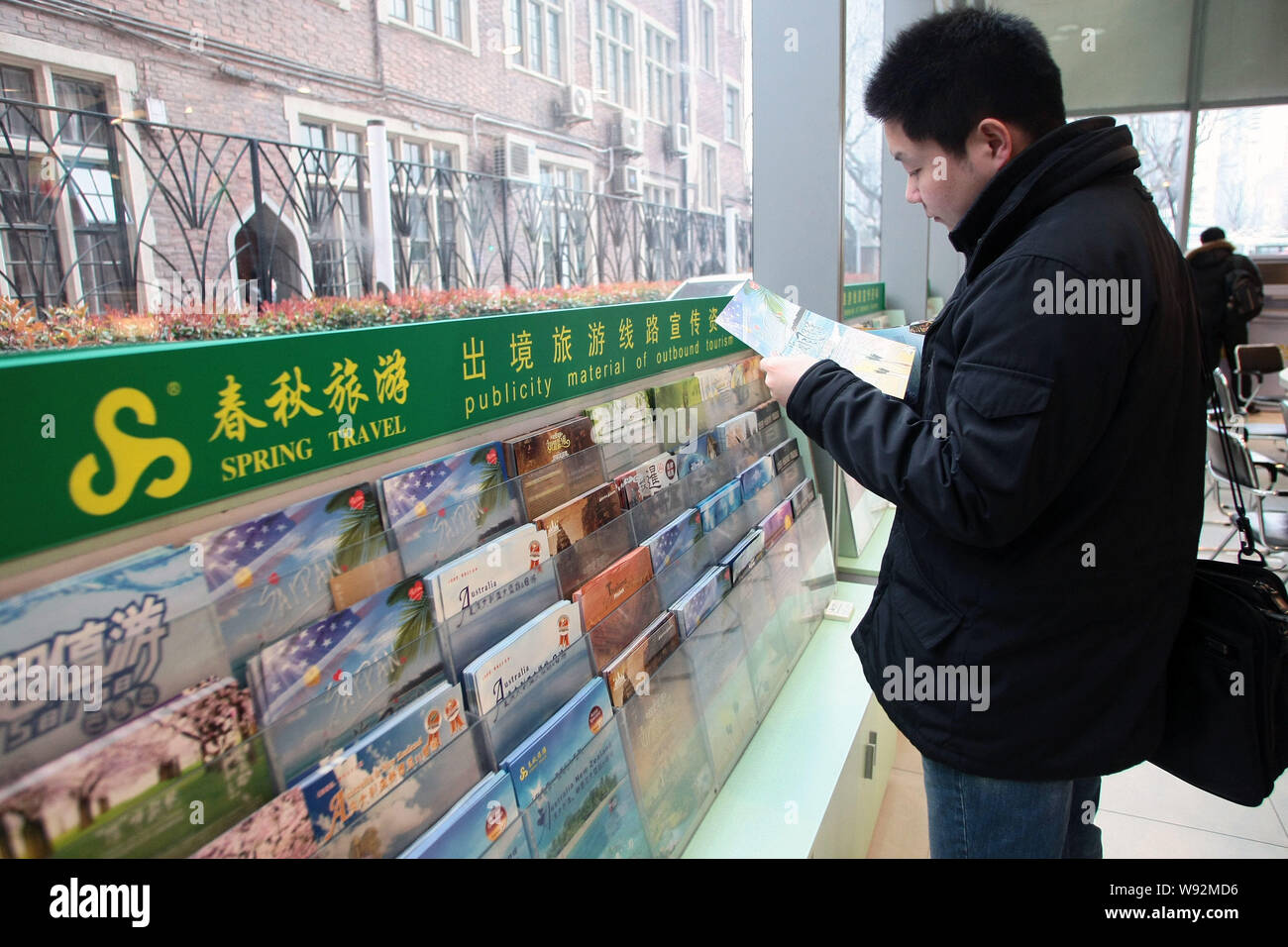 --FILE--A customer reads a travel brochure at a branch of Spring Travel in Shanghai, China, 21 March 2011.   The spending per person on international Stock Photo