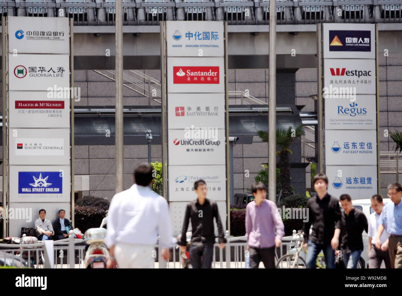 FILE--Pedestrian walk past a signboard (center) of Sinochem International,  Banco Santander, East West Bank, UniCredit Group and Medical Center of Pa  Stock Photo - Alamy