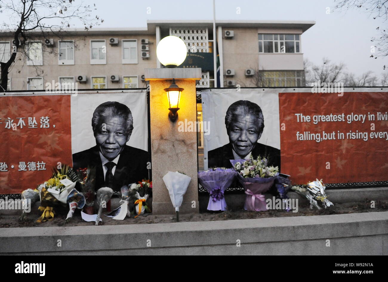 Bouquets are lined up in front of banners with photos of former South African President Nelson Mandela and his saying being displayed at the South Afr Stock Photo