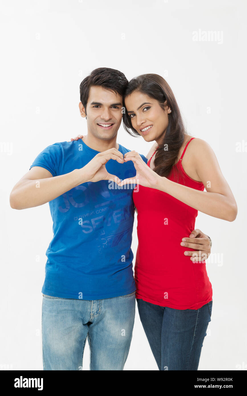 Young couple making heart shape with hands and smiling Stock Photo - Alamy