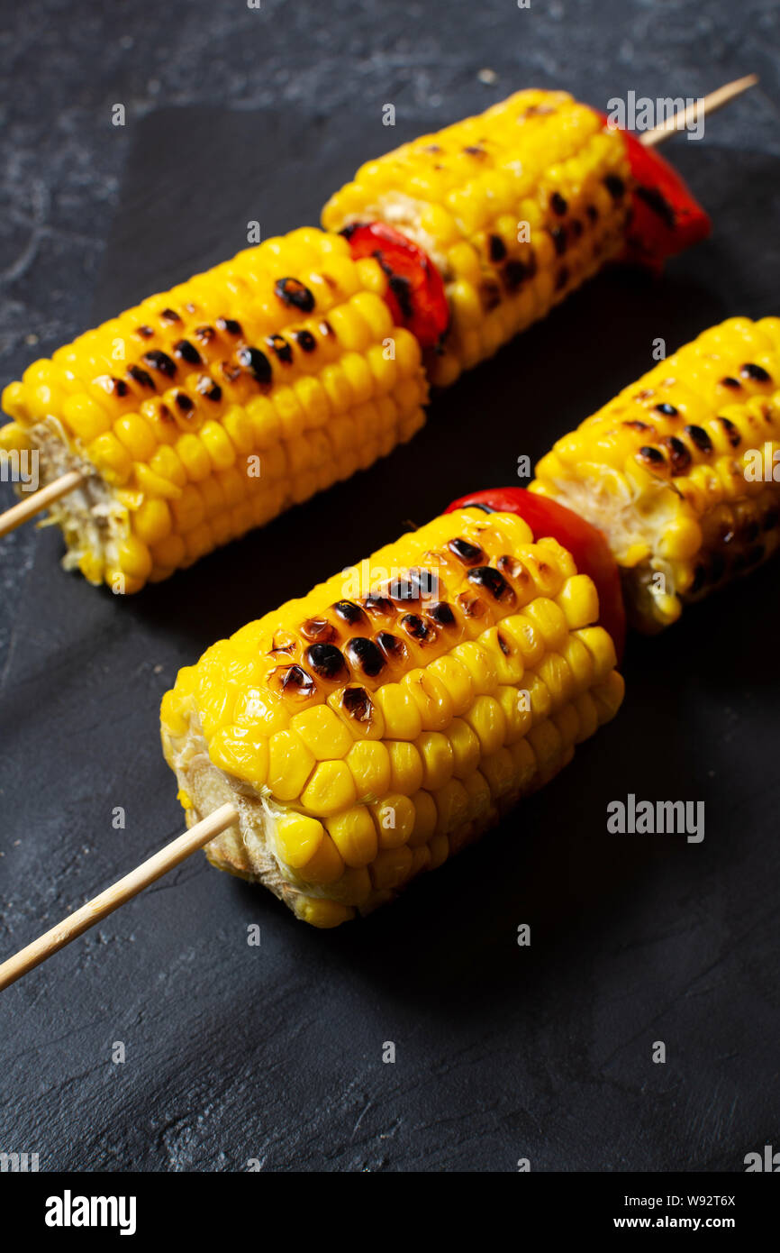 Corn Stick Grilled sweet corn on the sticks, black stone textured table Stock ...