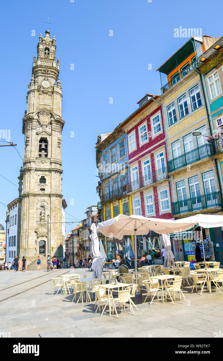 Porto, Portugal - August 31 2018: Famous Clerigos Church, Igreja e Torre dos Clerigos in Portuguese. Traditional houses with colorful facades, street with shops and restaurants. Sunny day. Stock Photo