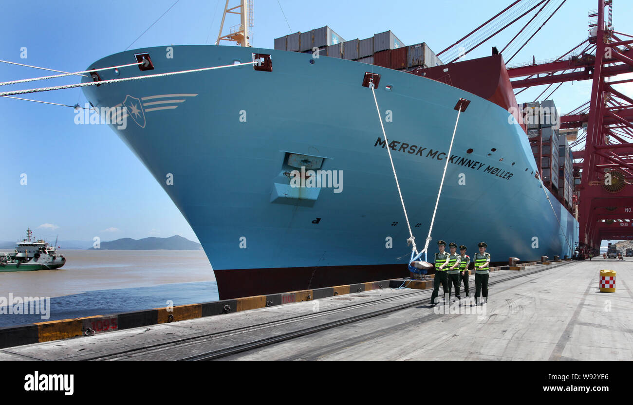 Chinese public securities walk past the Maersk Mc-Kinney Moeller Triple-E class container vessel, the worlds largest ship as it arrives at the Ningbo Stock Photo