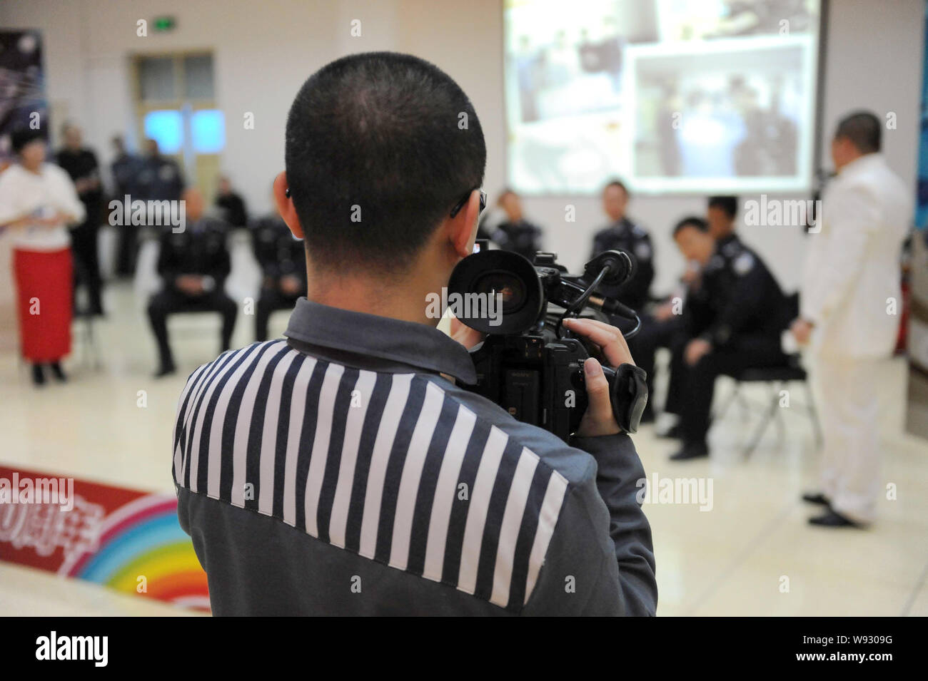 A Chinese inmate uses a camcorder to take videos of a performance to celebrate the 10th anniversary of Tianhe TV Station at Tianhe Prison in Beijing, Stock Photo