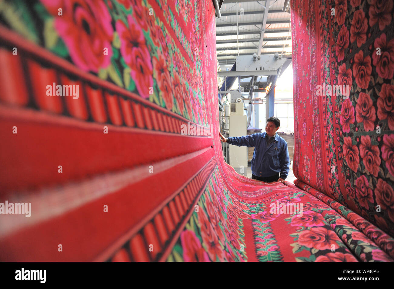 A Chinese worker monitors production of carpets at a factory in Rizhao city, east Chinas Shandong province, 21 November 2013.   Chinas manufacturing g Stock Photo