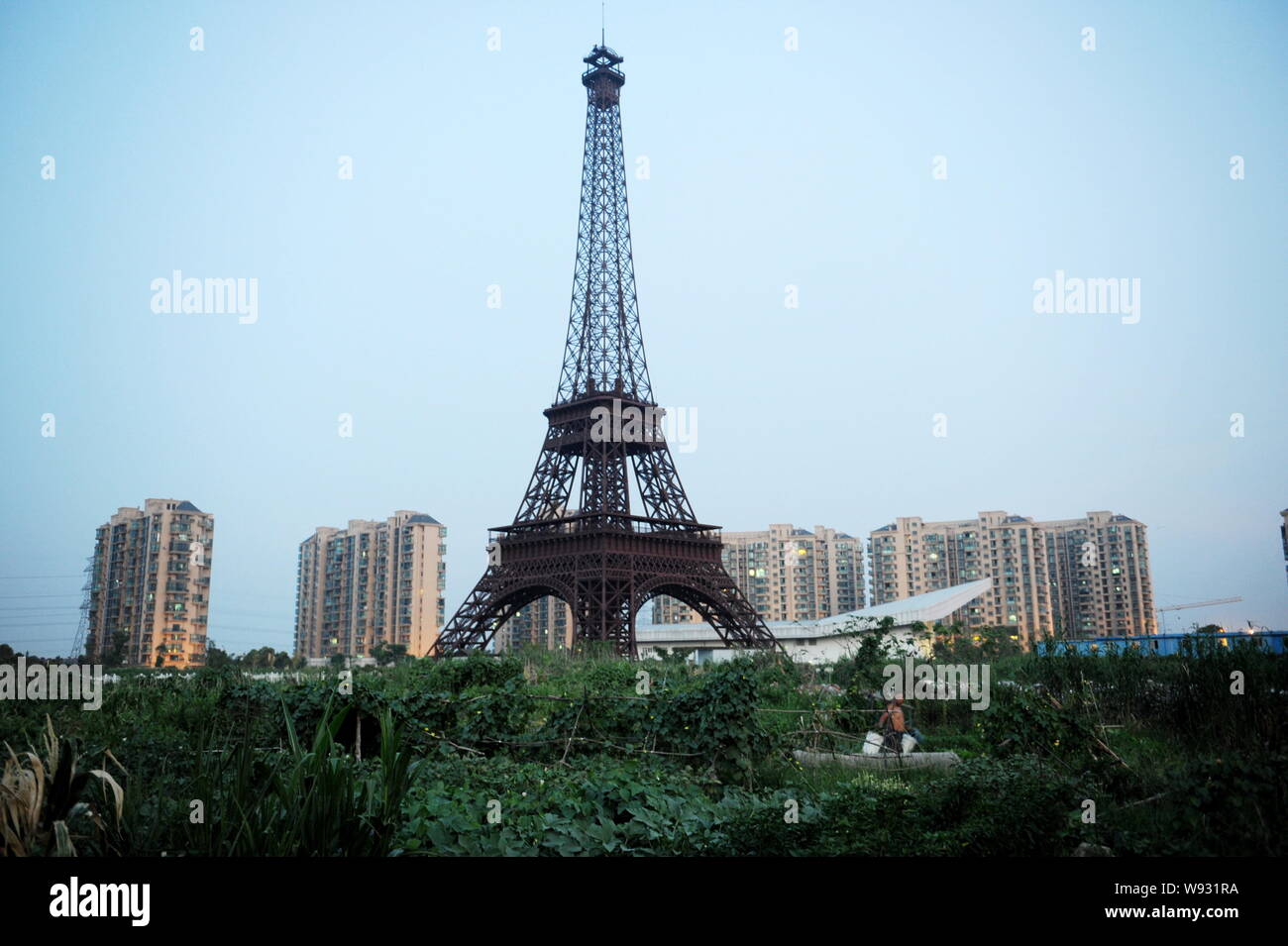 A Chinese farmer walks past the halfsized copy of Eiffel Tower at