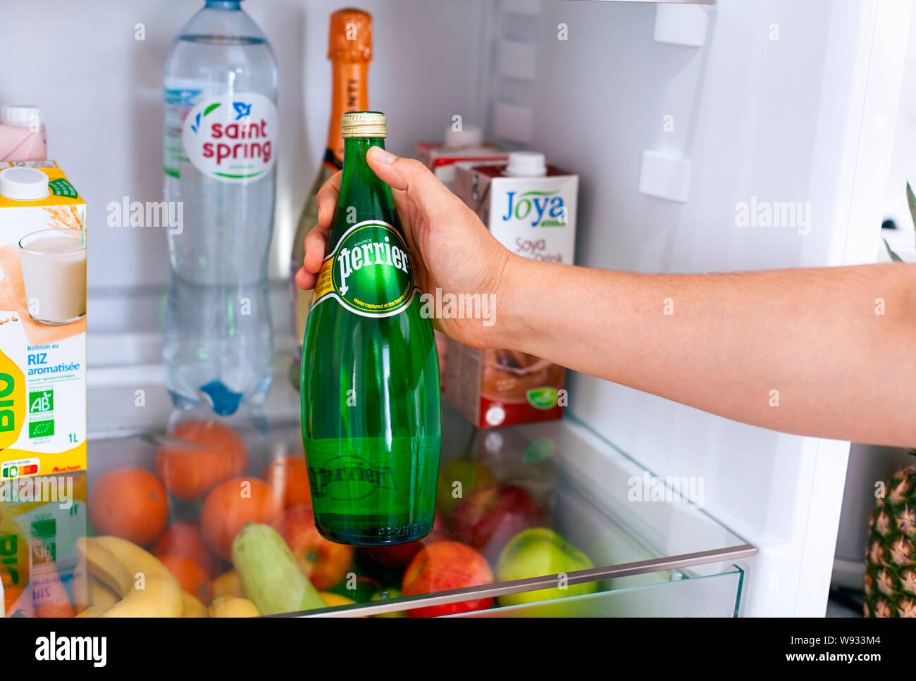 Tambov, Russian Federation - June 10, 2019 Person hand taking out Perrier water bottle from the fridge. Stock Photo