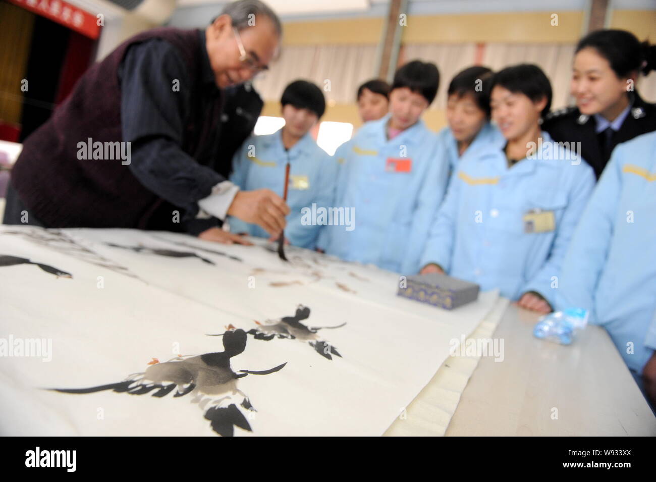 --FILE--Chinese inmates look at an artist drawing a Chinese painting at a female labor camp in Beijing, China, 9 December 2010.   Chinas top legislatu Stock Photo