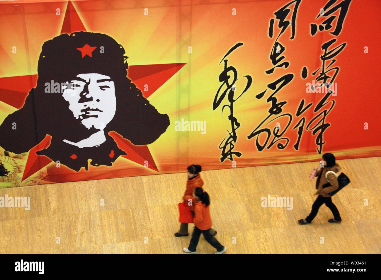 --FILE--Visitors walk past a poster of Lei Feng, the nations most famous Good Samaritan in Shandong museum in Jinan, east Chinas Shandong province, 18 Stock Photo