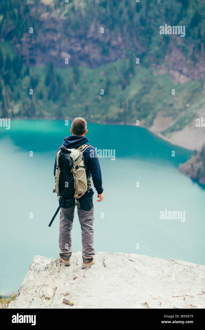 Hiker is standing on a cliff looking at the lake in GlacierNP, Montana Stock Photo