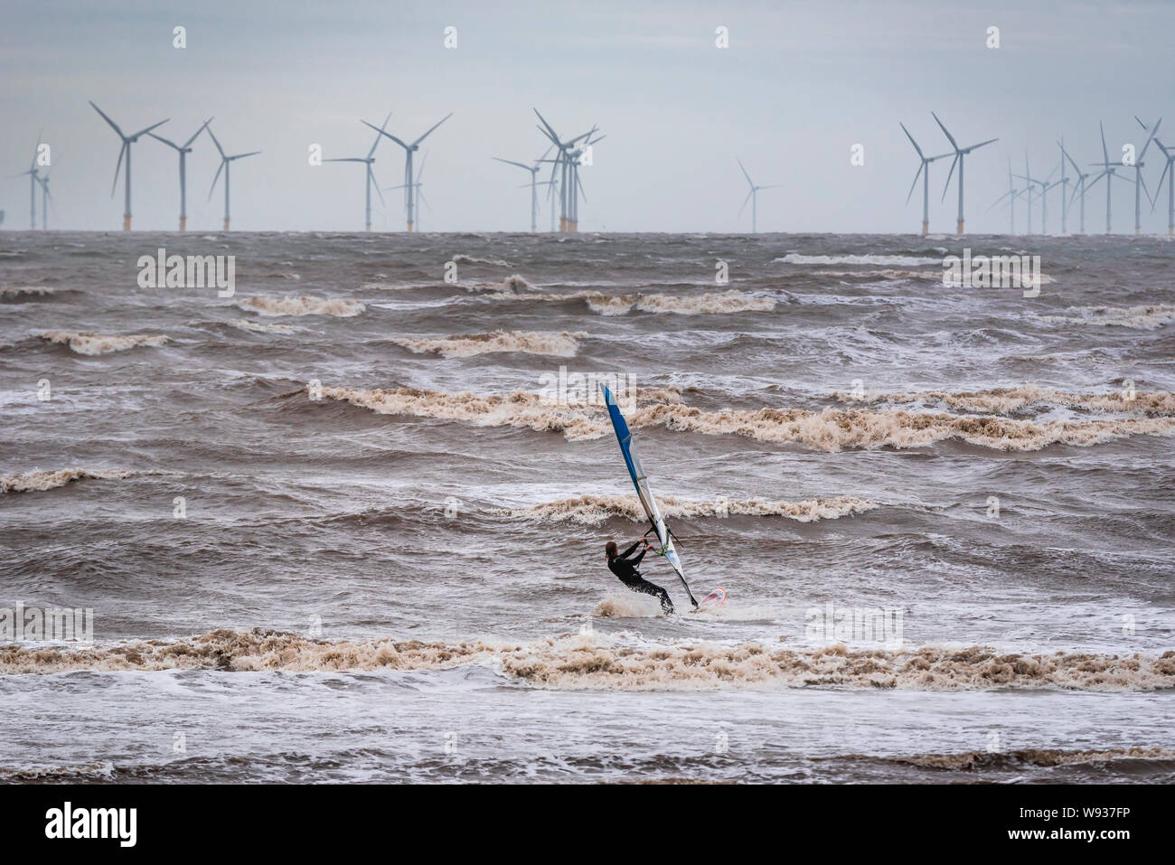 Windsurfer in the river Mersey at Crosby beach on a stormy day. Windpower. Liverpool Bay offshore windfarm. Clean green electricity. Stock Photo