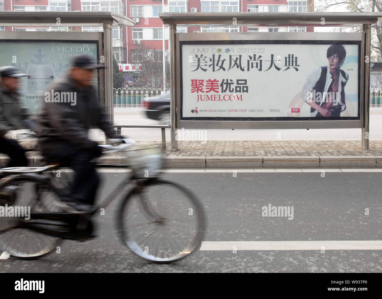 --FILE--Cyclers drive past an advertisement of Jumei.com in Beijing, China, 6 December 2011.   Online cosmetics retailers are quickly gaining ground i Stock Photo