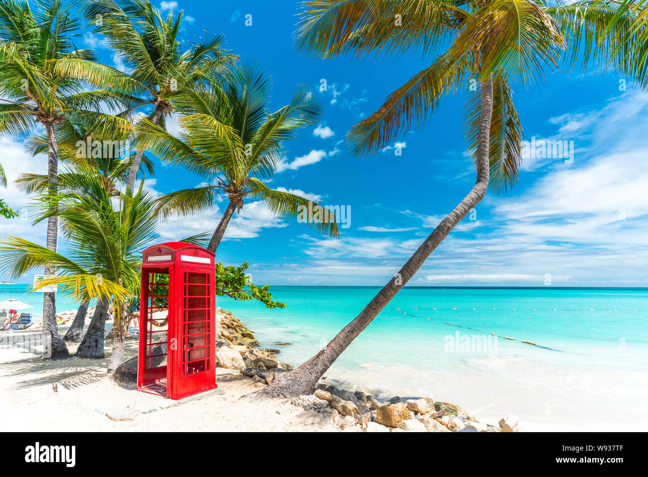 Iconic red british phone box in front of the clear Caribbean Sea, Siboney Beach, Dickenson Bay, Antigua Stock Photo