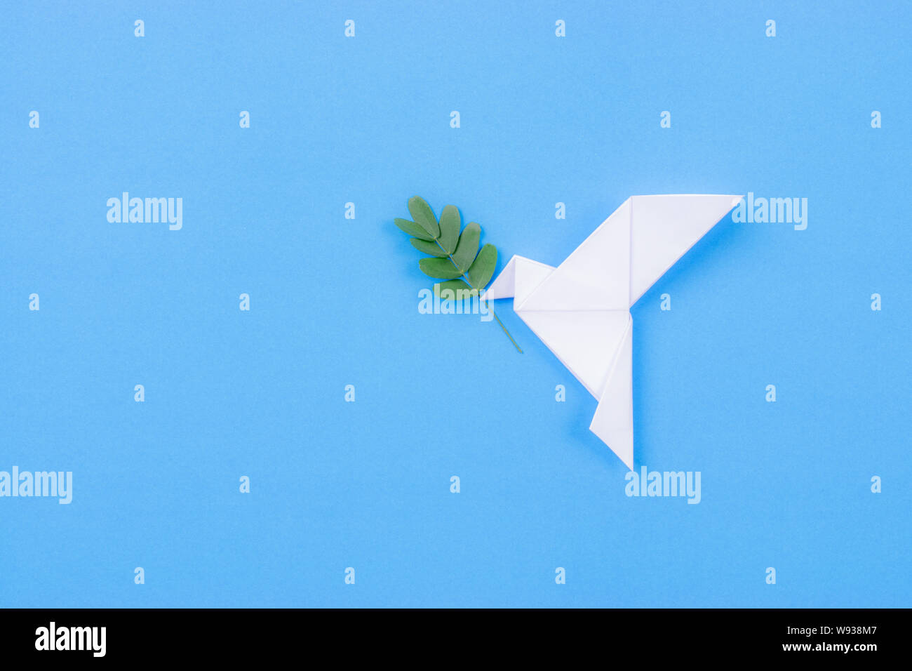 White dove made from paper carrying leaf branch. International day of peace. Stock Photo