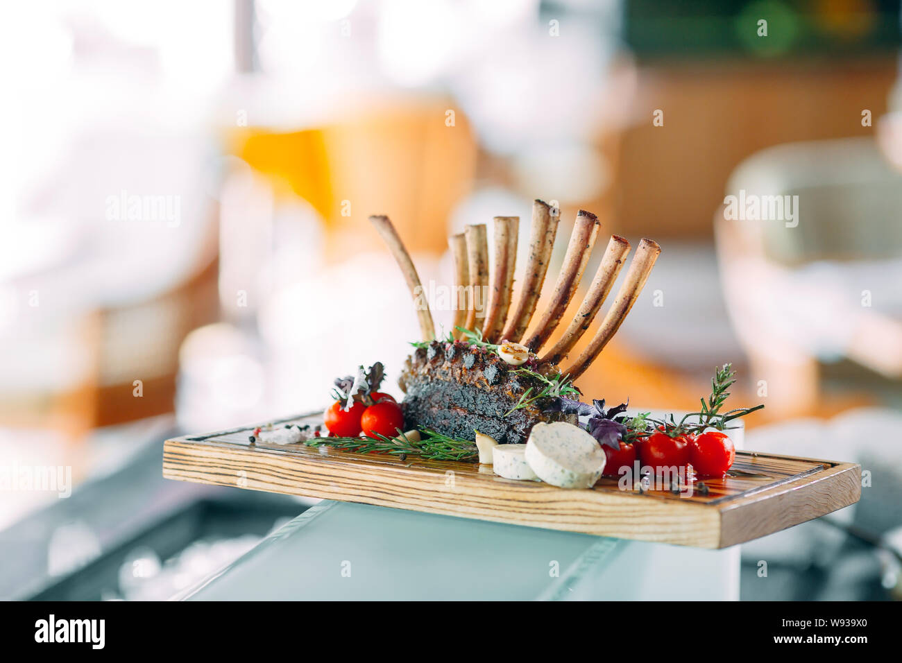 Dish Rack of Lamb with tomatoes on a wooden tray. Stock Photo