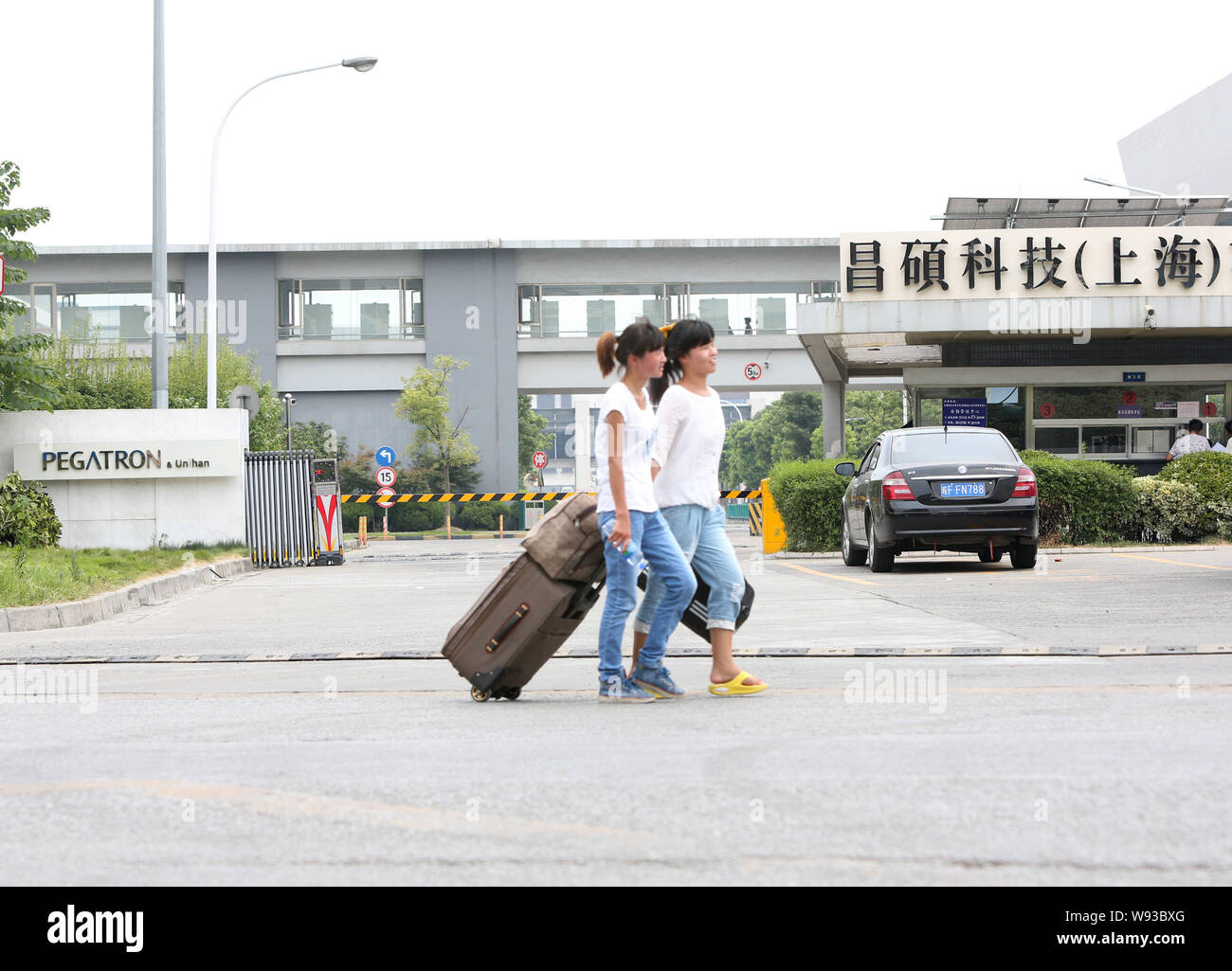 Chinese migrant workers walk past the plant of Pegatron-Unihan in Pudong, Shanghai, China, 25 July 2013.   A new report from a Chinese workers-rights Stock Photo