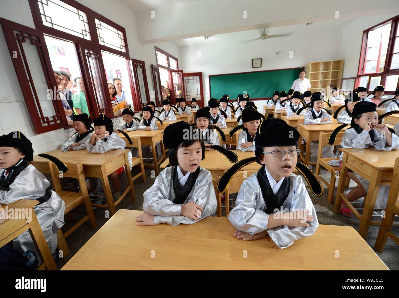 First-grade pupils wearing traditional Chinese uniforms sit in a classroom after the first writing ceremony of a new semester at Fuzimiao, or the Conf Stock Photo