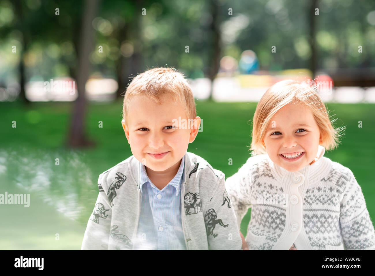 Two happy kids boy and a girl smiling together in the park outdoor ...