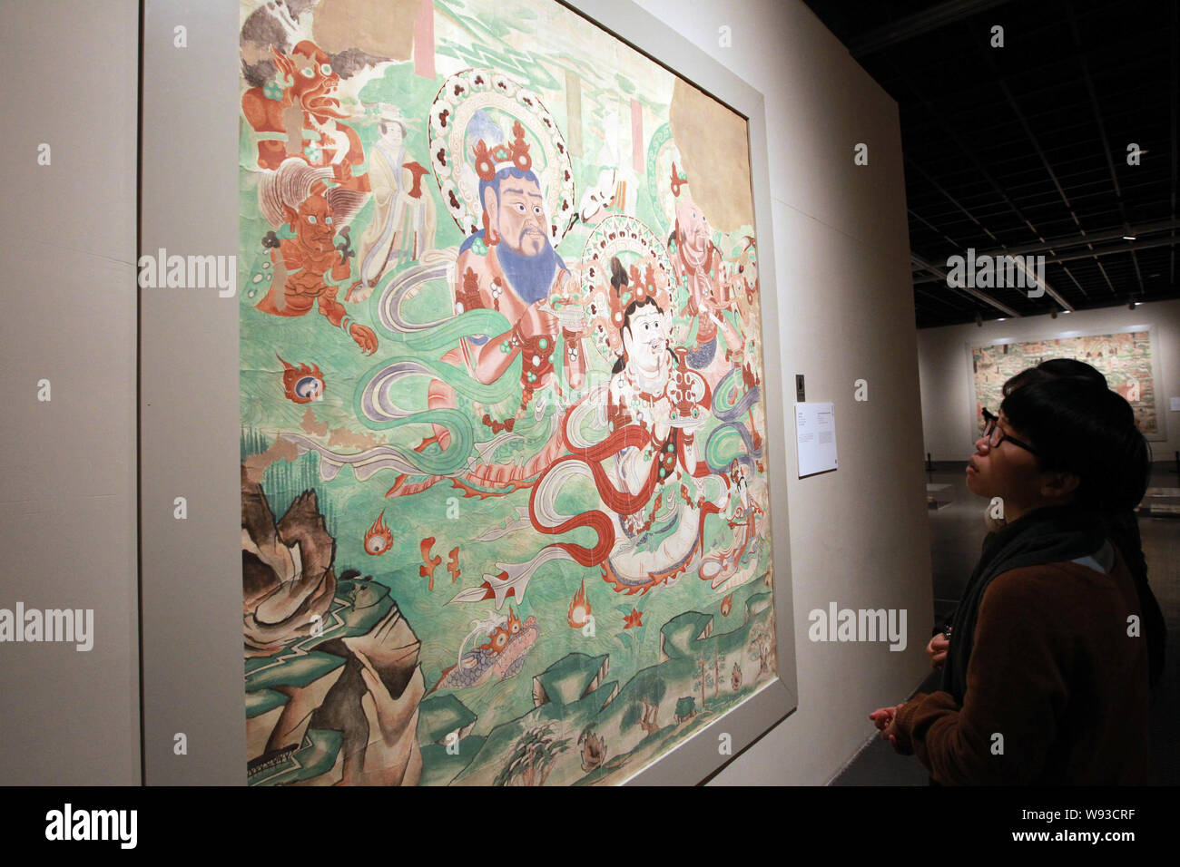 Visitors view a replicated fresco of the Mogao Grottoes during the ...
