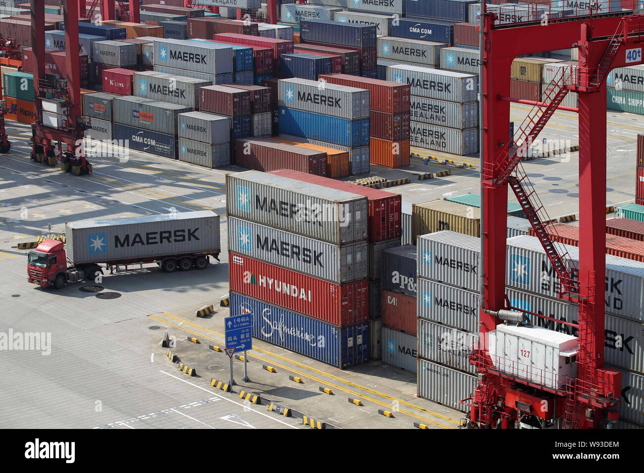 A container truck passes by piles of containers of Maersk and other ...