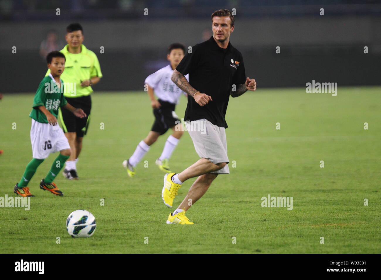 English soccer superstar David Beckham, front, plays football with young Chinese footballers during the half time of a 13th round match of the 2013 Ch Stock Photo