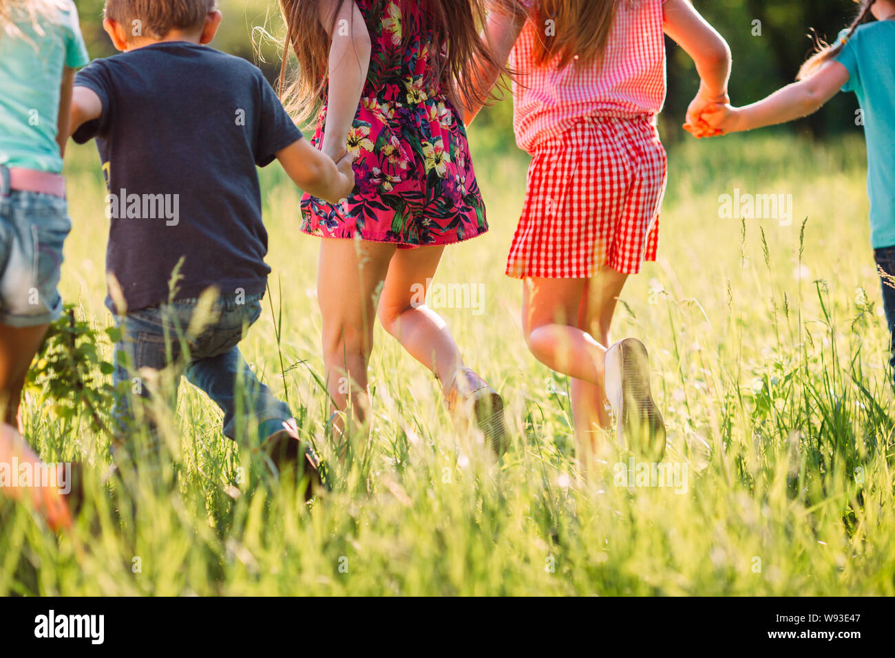 Large group of kids, friends boys and girls running in the park on sunny summer day in casual clothes . Stock Photo