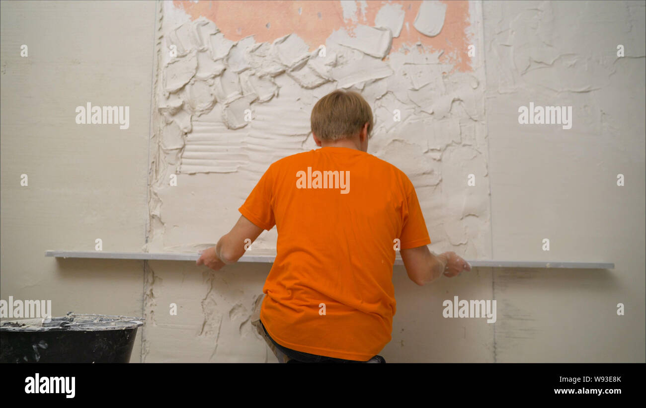 Worker smooths the plaster. Plasterer smoothing plaster mortar on ceiling with screeder Stock Photo