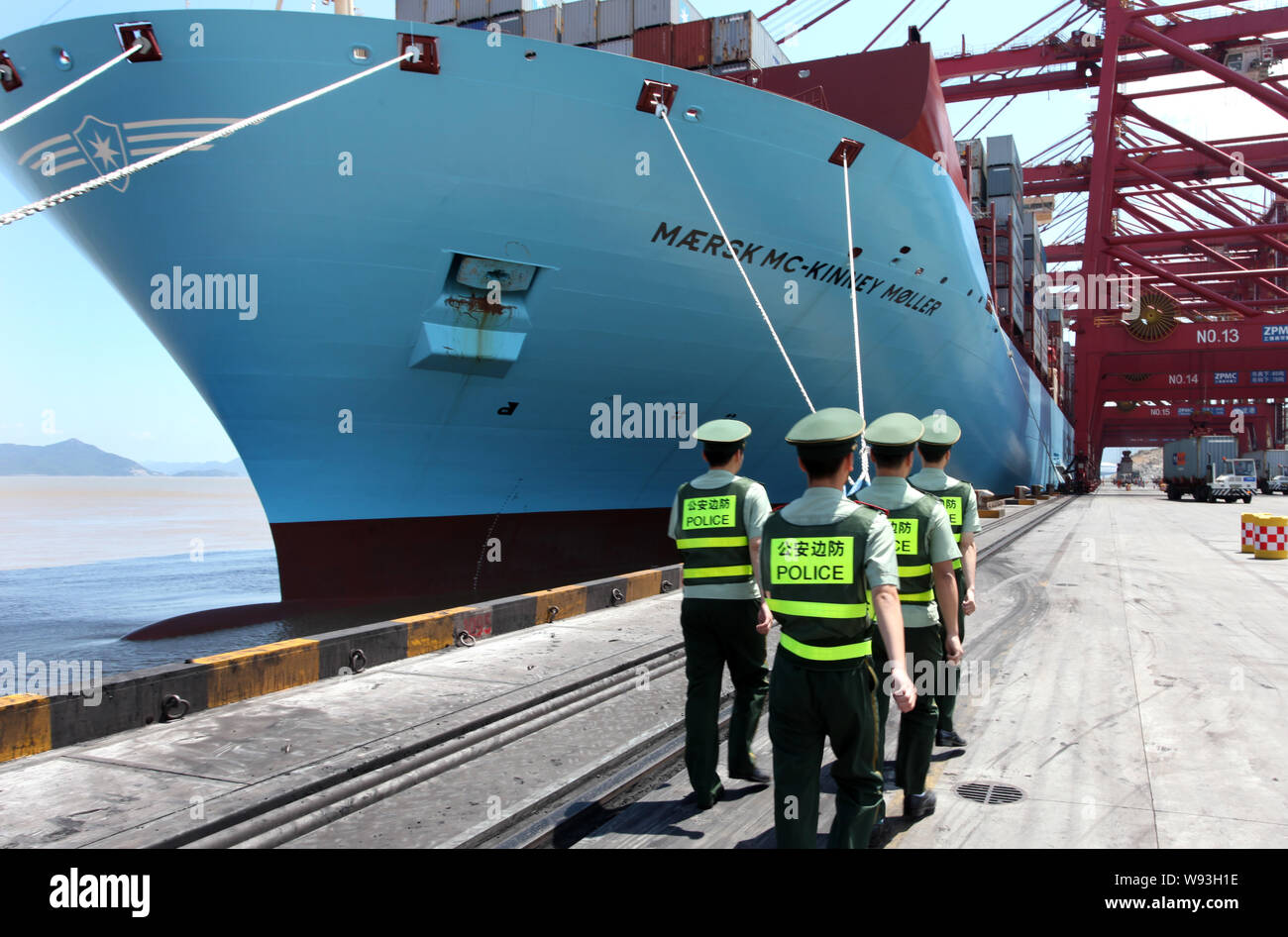 Chinese public securities walk past the Maersk Mc-Kinney Moeller Triple-E class container vessel, the worlds largest ship as it arrives at the Ningbo Stock Photo