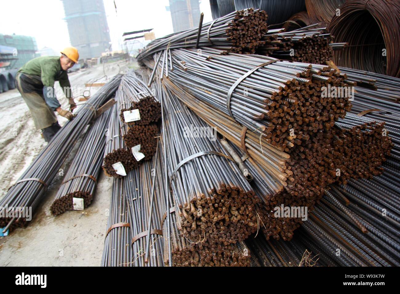 A Chinese worker fastens a cable to lift reinforcing steel rods at a construction site in Nantong city, east Chinas Jiangsu province, 7 September 2013 Stock Photo