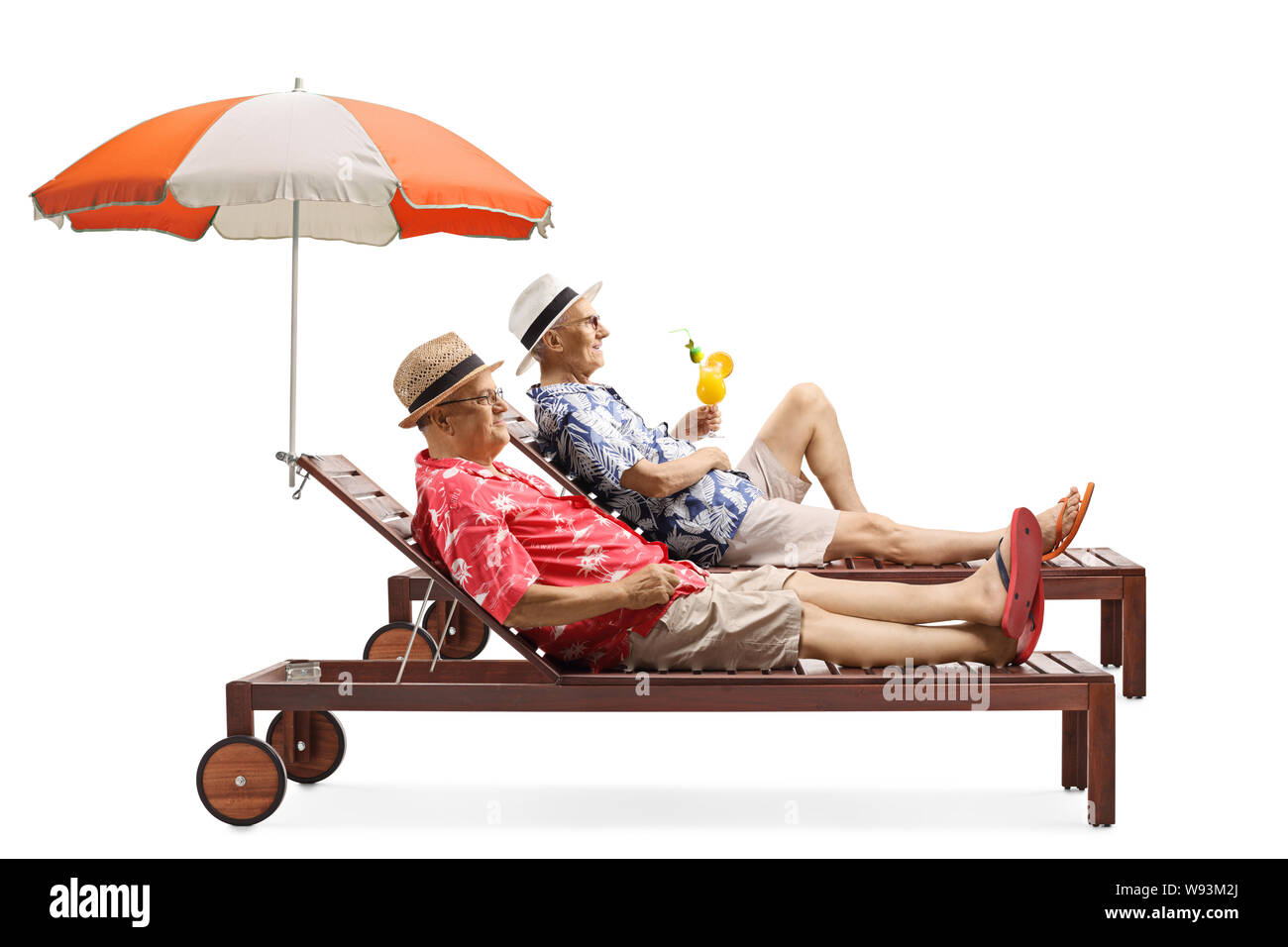 Full length profile shot of two senior men on vacation enjoying a cocktail on a sunbed under umbrella isolated on white background Stock Photo