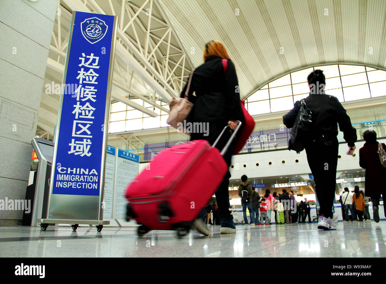 --FILE--Passengers travelling abroad walk past a signboard of China Immigration Inspection at the Qingdao Liuting International Airport in Qingdao, ea Stock Photo