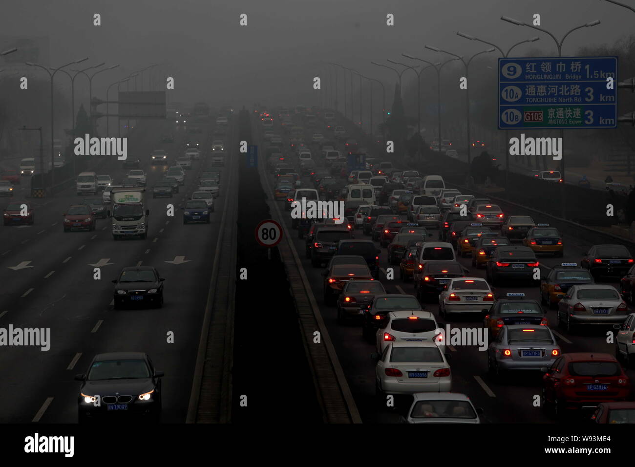 Cars travel on a road in heavy smog in Beijing, China, 30 January 2013.   Endless lines of slow-moving cars emerge like apparitions and then disappear Stock Photo