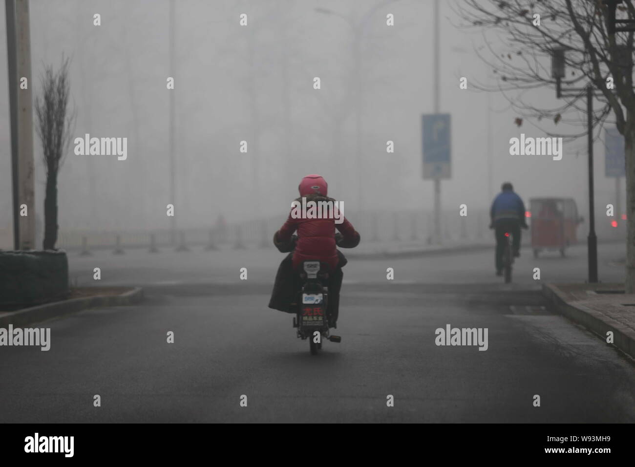 Cyclers drive on a road in heavy smog in Beijing, China, 17 February 2013.   Thick fog forced the Capital Airport and highways in Beijing to close thi Stock Photo