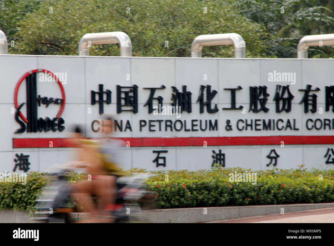 --FILE--Cyclers drive past a branch of Sinopec  in Haikou city, south Chinas Hainan province,1 December 2012.   China Petrochemical Corp., the country Stock Photo