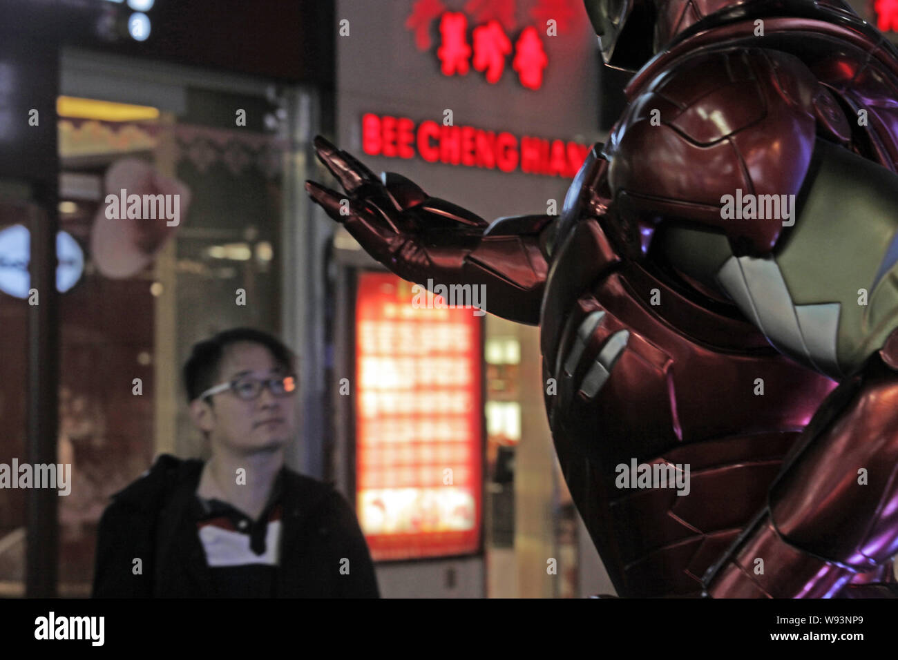 --FILE--A Chinese man looks at a sculpture of Iron Man set up for the promotion of the new movie, Iron Man 3, at Shanghai DaNing international shoppin Stock Photo