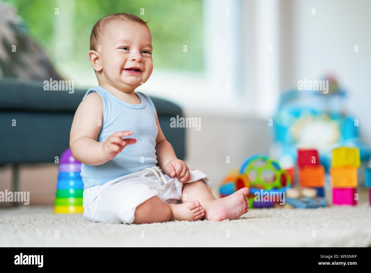 Cute smiling baby boy sitting on floor in living room Stock Photo - Alamy