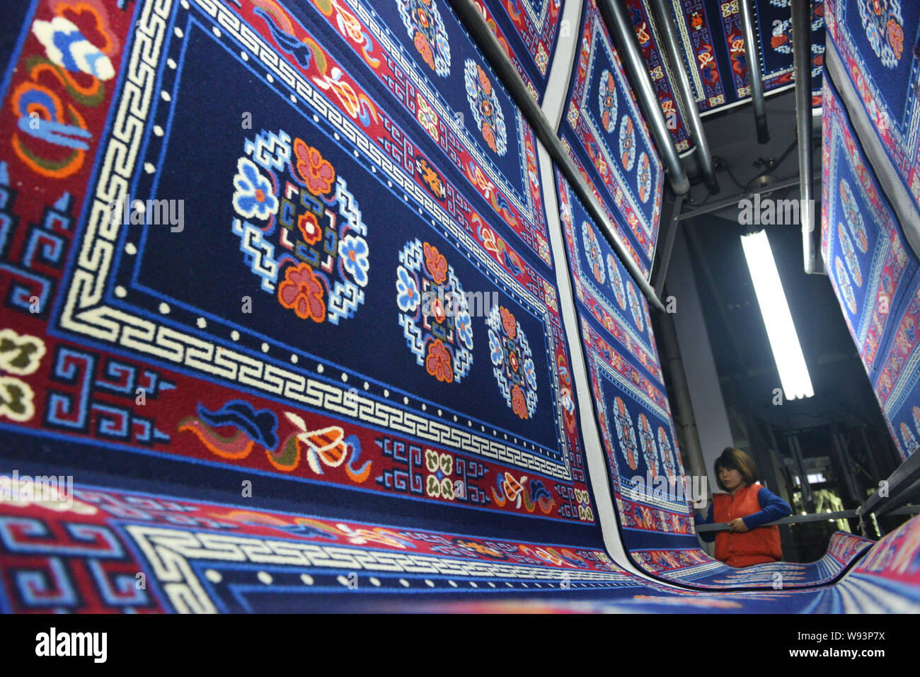A female Chinese worker monitors production of carpets at a textile factory in Linchi town, Zouping county, Binzhou city, east Chinas Shandong provinc Stock Photo